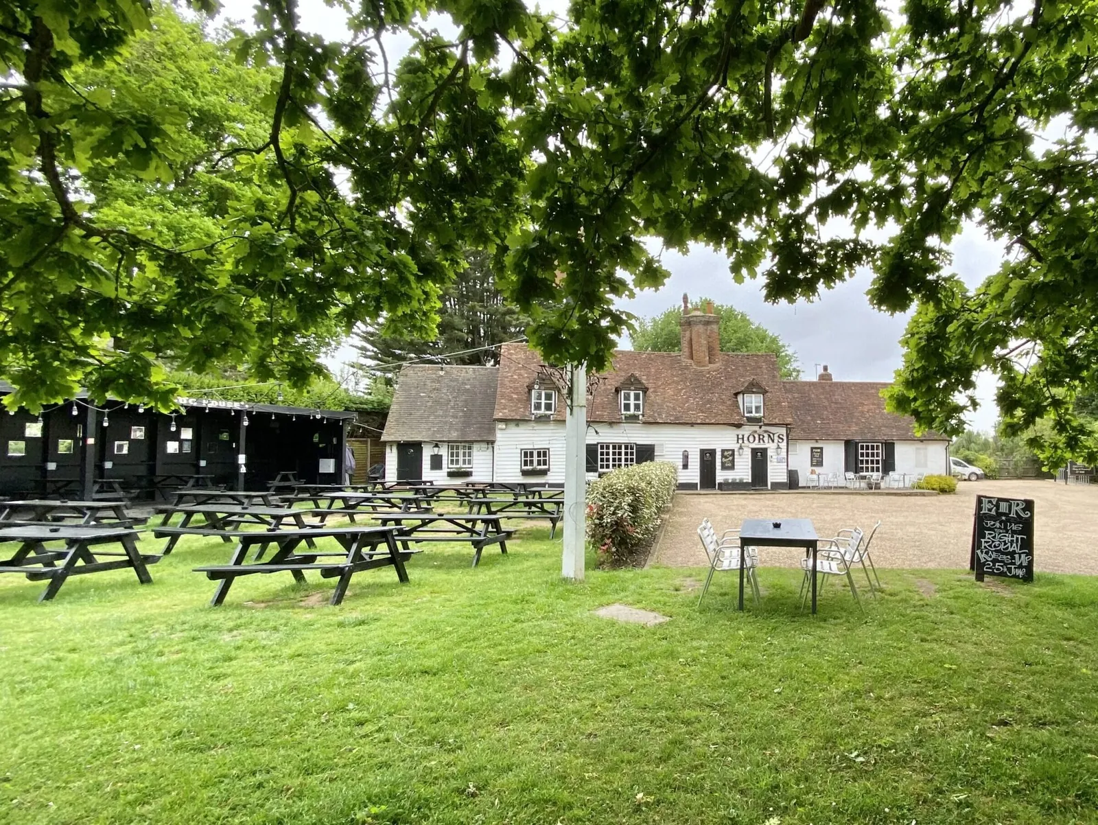 Tables set out under the trees in the garden at The Horns