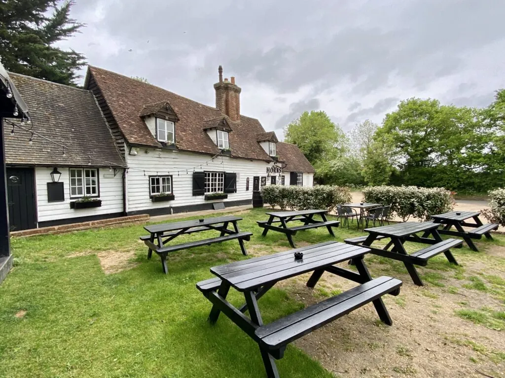 Outdoor tables beside The Horns and the village green